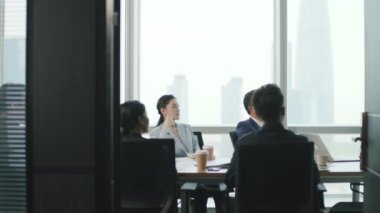 Asyalı iş adamlarından oluşan bir ekip modern ofis konferans salonunda toplanıyor.