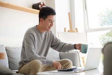 Mutlu ve gülümseyen Asyalı şirket yöneticisi iş arkadaşlarıyla ya da müşterileriyle video görüşmeleri sırasında kadeh kaldırmayı öneriyor.
