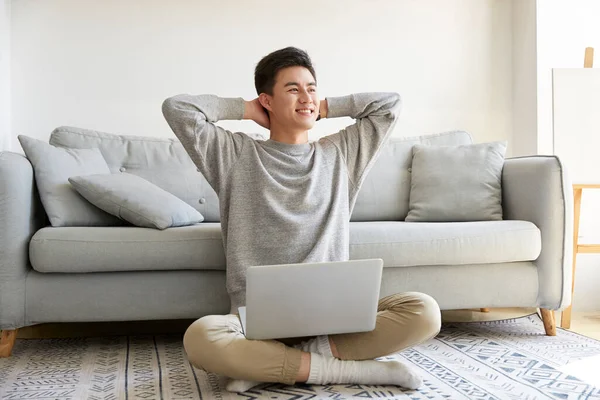 幸せな若いアジア人のビジネスマンが家に座ってカーペットの上でノートパソコンを使って仕事をする幸せと笑顔 — ストック写真