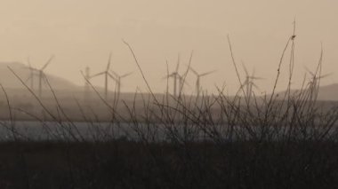 Gün batımında bulutlu bir öğleden sonra rüzgar türbinleri döner hareket.