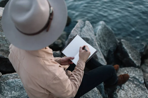 Reisende Med Stilige Klær Hipsterhatt Skriver Notater Håndlaget Notisblokk Mann – stockfoto