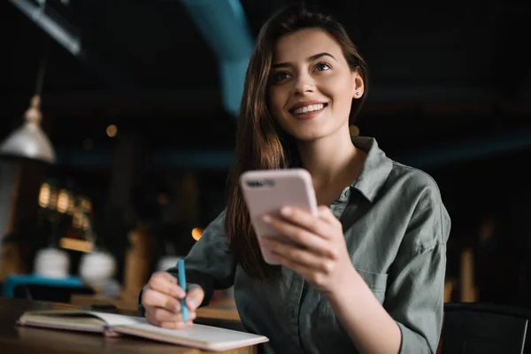 Proje için araştırma bilgi online istimal hareket eden telefon genç çekici iş kadını ile güzel yüz ve gülümseme notları not defterinde, yapma. Şirin ve olumlu erkek Smartphone becerikli alet içinde modern ofis holding. 