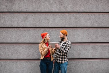Tablet bilgisayar ayakta birlikte sokakta kullanarak çift gülümsüyor. Olumlu ve şık kadın bir gadget sakallı hippi arkadaşına verir..