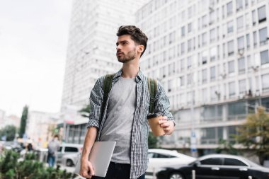 Dizüstü bilgisayar ve kahve, o bekleyen taksi açık havada tutan sakallı hippi adam iyi giyimlisin. Sokakta yürüyen ve başlangıç projesi hakkında düşünme yakışıklı başarılı işadamı portresi.