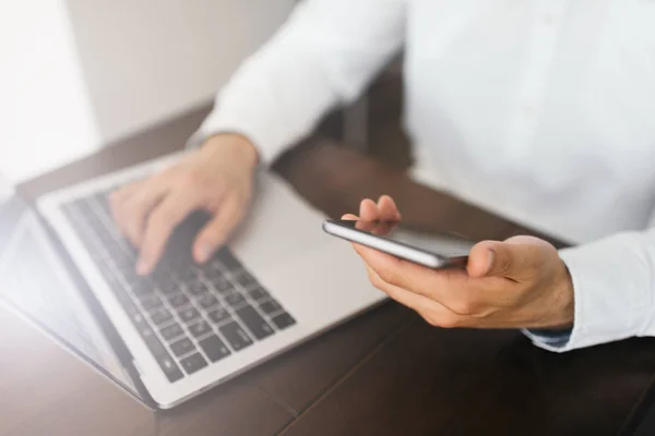 Dizüstü bilgisayar, akıllı telefon ve internet bağlantısı kullanarak proje online ofiste oturan işadamı eller. Başarılı bir iş. Telefon, holding adam klavyede yazarak mobile uygulaması ile online alışveriş. Uzak iş. Serbest. 