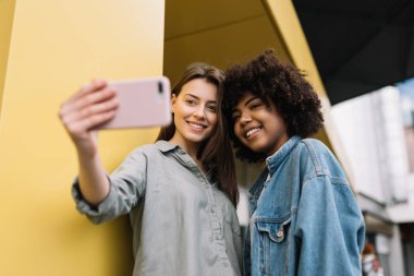 Pozitif hipster dostları cep telefonu tutuyorlar, fotoğraf çekiyorlar, gülüyorlar, evde birlikte eğleniyorlar. Karışık yarış blogcuları şık günlük kıyafetler giyip akıllı telefon ve internet bağlantısı kullanarak online video yayınlıyorlar.