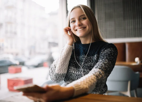 Piękna Uśmiechnięta Kobieta Słucha Muzyki Korzystając Słuchawek Smartfona Loftowej Kawiarni — Zdjęcie stockowe