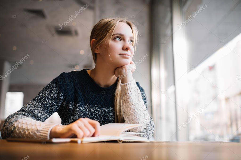 Young attractive student studying at home, distance learning. Cute caucasian woman with beautiful blue eyes sitting in loft cafe, planning working process, thinking about project. Exam preparation