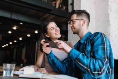 Şık hipster çift, gıda fotoğraf yapma loft kafede yok iyi bir ruh hali. Cep telefonu kapalı tutan şirin kadın güzel gülümseme ve birlikte, onun komik blogger arkadaş iletişim.