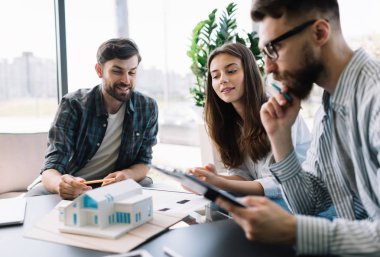 Mimarlar modeli ev ve planları ile çalışma. Ekip çalışması. Beyin fırtınası. İletişim. İşbirliği yapın. Çatı katı modern ofis Projesi'nde kurmak için yenilik teknoloji ve yaratıcı çözüm kullanan mühendisler geliştiriciler grubu. Başarılı iş. 