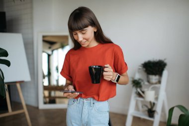 Sohbet, smartphone, kullanarak kırmızı tişörtlü onay posta kutusu, başarılı ve şık kadın portresi bilgi araştırma. Kahve modern ofis çalışma proje tutan hipster kadın. Freelancer iş başında. 