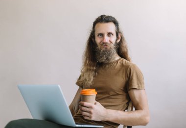 Yetenekli gülümseyen bilişim uzmanı yazılım geliştirir ve test eder, dizüstü bilgisayar ve internet kullanarak program ve uygulama kodunu yazar ve çevrimiçi çalışır. Mutlu sakallı hippi kahve içiyor. İş yerindeki yazılım geliştiricisinin portresi