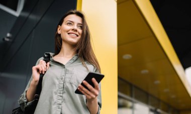 Güzel gülümseme ve online bankacılık, sohbet, düşünme ve planlama başlangıç proje ayakta iş merkezine yakın modern cep telefonu kullanarak yüz emin mutlu işkadını. Başarılı bir iş için yaratıcı bir fikir. Kariyer. 