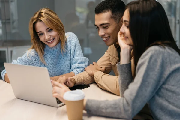 İnternette dizüstü bilgisayar ve internet kullanan mutlu çok ırklı üniversite öğrencileri birlikte çalışıyorlar, işbirliği yapıyorlar, gülüyorlar, internette bilgi araştırıyorlar. Webinar ve eğitim kurslarını izleyen arkadaşlar