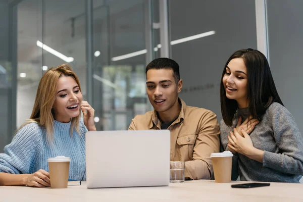 Dizüstü bilgisayar kullanan izlemek için eğitim kursları, online eğitim, iletişim, dil öğrenme mutlu çok etnik hipsters arkadaşlar birlikte masadan heyecanlı yüzü olan grup. Ekip çalışması işbirliği beyin fırtınası iletişim 
