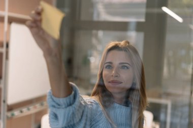 Yapışkan notlar kullanan güzel bir kadın. Üniversite öğrencisinin portresi, çalışma projesi, sınav hazırlığı, öğrenme dili, iş yerinde kargaşa kullanarak planlama stratejisi. Beyin fırtınası.