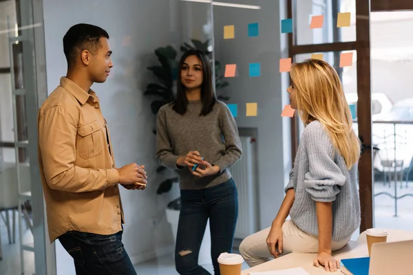 Group of multiracial business people working project, planning strategy, talking, discussion creative idea in modern office. Colleagues meeting, collaborate, using sticky notes and scrum