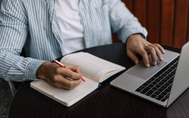 Adamın elleri çalışma süreci planlama, strateji, bilgi Web sitesinde arama geliştirme defter, not alma görüntüsünü kapatın. Serbest. Uzak iş. Başarılı bir iş adamı çalışma proje online dizüstü bilgisayar ve Not Defteri kullanma office. 
