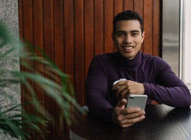 İndirimli satış ile online alışveriş için modern mobile uygulaması ile akıllı telefon kullanan Afrikalı-Amerikalı adam gülümsüyor, nakit geri, düşük fiyatlar. Mutlu genç kafede kahve içme kısa mesaj, sohbet, gönderen adam. Sosyal medya kavramı 