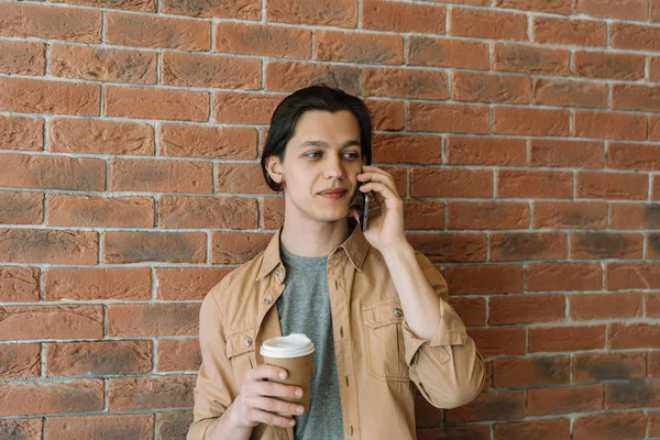 Aantrekkelijke Jongeman Met Behulp Van Mobiele Telefoon Kopje Koffie Houden — Stockfoto