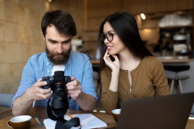 Dijital fotoğraf makinesi tutan profesyonel fotoğrafçı. Gülümseyen hipsters birlikte serbest proje çalışıyor. Sakallı adam ve güzel Asyalı kadın fotoğraf kamera, iletişim, gülüyor bakıyor 