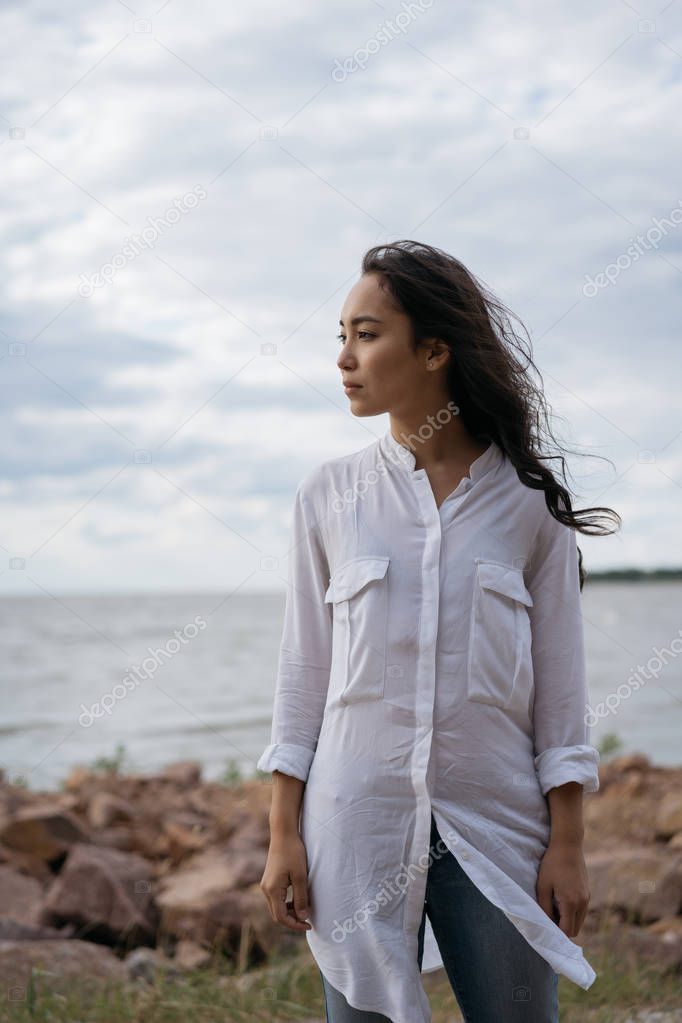 Beautiful asian woman walking along beach, breathing fresh air, thinking, enjoying view of nature, relaxing near river. Pensive Korean girl looking for inspiration outdoor 