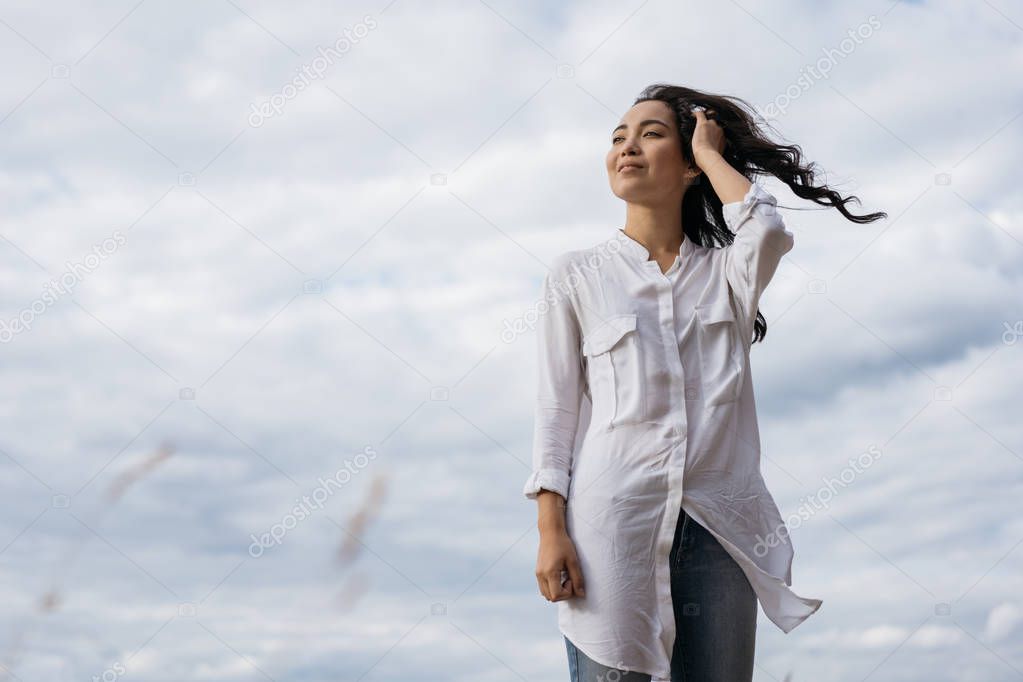 Portrait of cheerful asian woman walking in field, breathing fresh air. Happy Korean girl looking for inspiration, enjoying beautiful landscapes, windy weather and relaxing outdoor. Positive lifestyle, emotional moments concept 