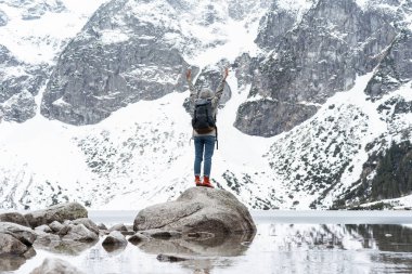  Dağların yanında taş üzerinde duran, güzel manzaraların tadını çıkaran, el ele tutuşan seyahat sırt çantası olan kadın yürüyüşçünün arka görünümü. Aktif yaşam tarzı Seyahat kavramı Macera Özgürlük