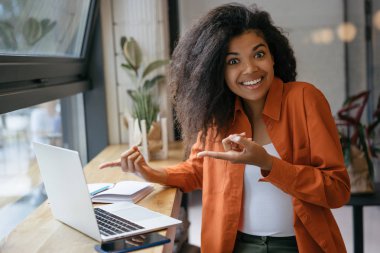 Genç neşeli Afro-Amerikan kadın dizüstü ekranda iki parmak işaret. Duygusal hipster kız dizüstü bilgisayar kullanarak, online alışveriş, yemek siparişi, bilet rezervasyon  
