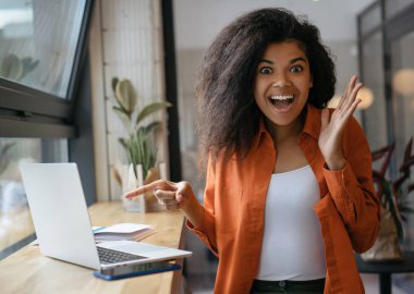 Heyecanlı Afro-Amerikan kadın dizüstü ekranda parmak işaret. Duygusal hipster kız alışveriş online indirim satış, düşük fiyat, nakit geri. Kara Cuma konsepti 