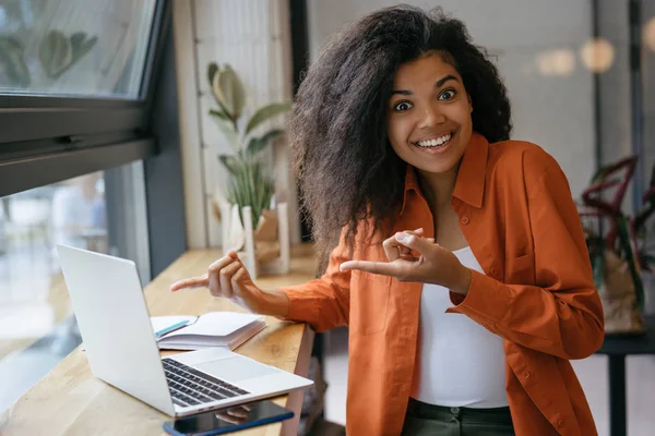 Genç neşeli Afro-Amerikan kadın dizüstü ekranda iki parmak işaret. Duygusal hipster kız dizüstü bilgisayar kullanarak, online alışveriş, yemek siparişi, bilet rezervasyon  