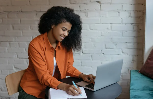 Başarılı bir üniversite öğrencisi, Laptop bilgisayar ve internet kullanarak dil öğreniyor. Genç mutlu Afrikalı Amerikalı kadın internet sitesinden iş eğitimi kurslarını izliyor, not alıyor. 