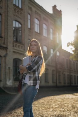 Üniversiteye yürüyen bir öğrenci. Eğitim konsepti. Sırt çantası ve kitaplarıyla parkta duran mutlu güzel bir kadının portresi.