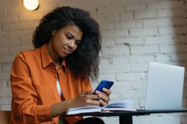 Cep telefonu tutan iş kadını, e-postaları kontrol eden, ofiste çalışma sürecini planlayan, internetten iletişim kuran. İş yerinde serbest çalışan bir kadın, cep telefonu, internet, dizüstü bilgisayar kullanıyor.