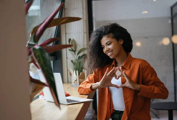 Abonelerle başarılı bir blog yazıcısı iletişimi, canlı yayın, görüntülü sohbet. Genç ve güzel bir Afro-Amerikalı kadın interneti video görüşmesi için kullanıyor, modern kafede oturuyor, gülüyor. 