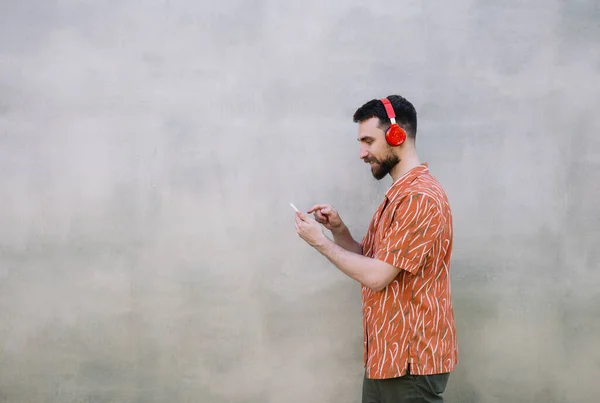 Jonge Man Met Een Baard Draagt Een Rode Hoofdtelefoon Luistert — Stockfoto