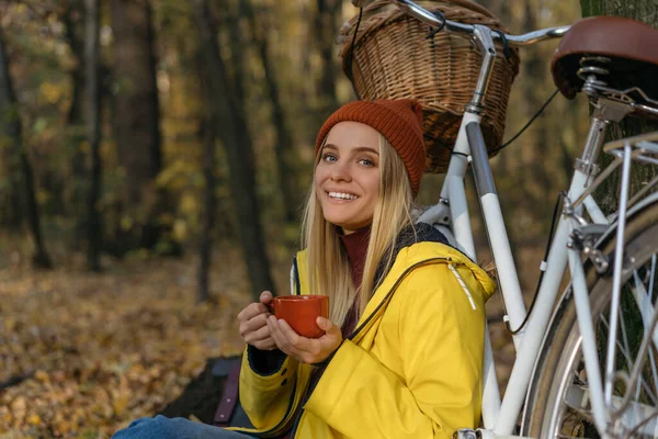 Vacker Kvinna Avkopplande Höstskogen Håller Kopp Kaffe Tittar Kameran Ler — Stockfoto