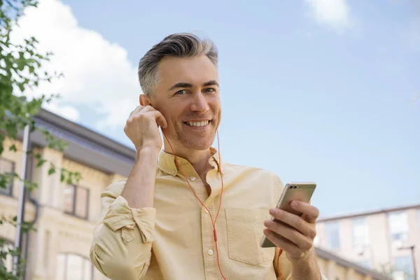 Yakışıklı Olgun Bir Adam Cep Telefonu Tutuyor Kırmızı Kulaklıkla Müzik — Stok fotoğraf