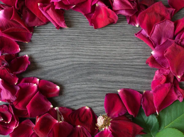 Flat lay of withered rose and petals making a circle in a wooden background leaving a negative space for a message