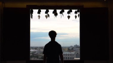 Tapınağın dışında pencereden bakarak siluet genç adam
