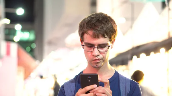 Arka planda - yayımlanan modeli kullanarak Smartphone ile odak insanların içinden arama gözlüklü Genç beyaz adam