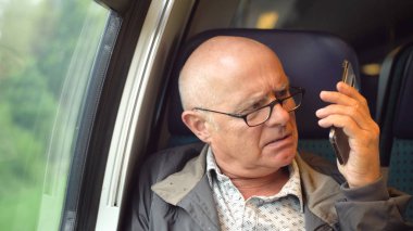 Angry man talking on mobile phone in train clipart