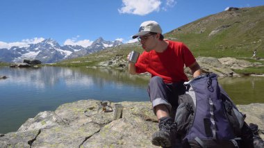 Mutlu genç Hiker pişirme çay / kahve üzerinde kamp sobası
