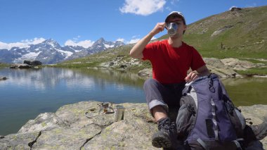 Mutlu genç Hiker taze içme çay veya kahve yapılan dağlarında mola sırasında