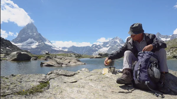 Hiker Packing Out Food and Eating Snack on Break up in Mountains