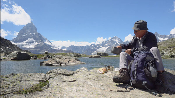 Hiker Cooking Food in Mountains