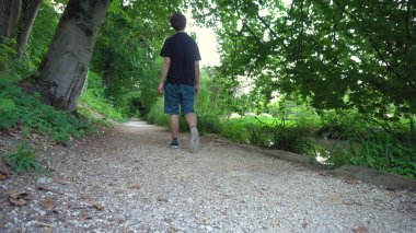 Causually giyinmiş genç beyaz adam pastoral ormanda yürüyüş