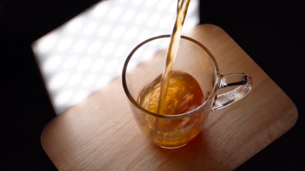 Verter té en tiempo real en la taza de vidrio y luego tomar la taza a mano — Vídeos de Stock