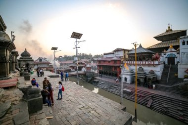 Katmandu, Nepal - 4 Kasım 2018: Pashupatinath Tapınağı tesislerinde Bagmati Nehri'nin kıyısında oturan insanlar.