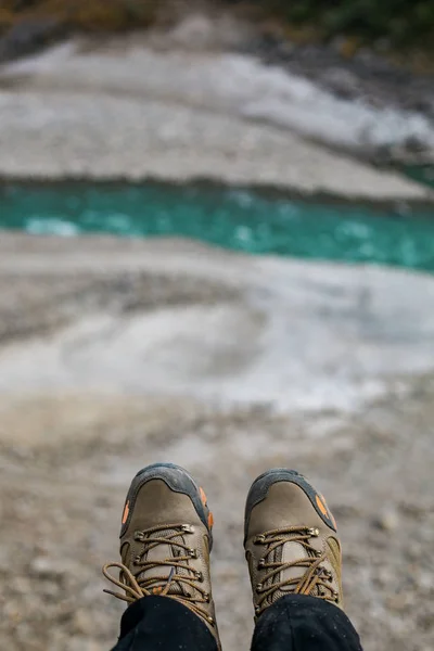 Shoes and serenity. Legs hanging with river flowing in the background